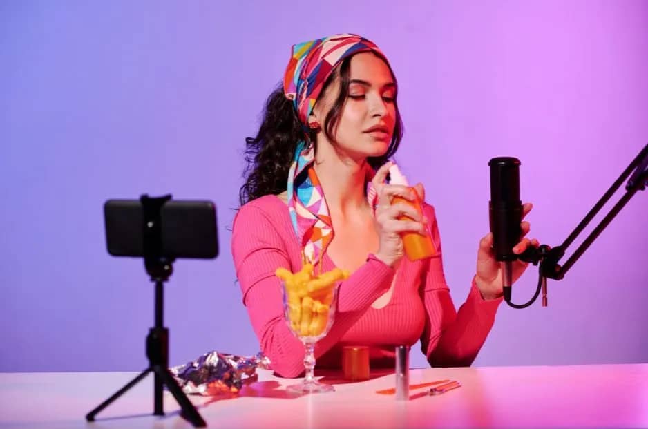 Une femme qui prépare son podcast avec son micro et son téléphone filme en même temps en vidéo.